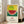 May include: Framed poster with colorful pointillist-style watermelon artwork featuring green striped rind, red flesh with black seeds, and blue accents on yellow dotted background. Japanese characters and English text about courage below the illustration. Light wood frame leaning against white wall next to beige sofa in bright living room with large windows.