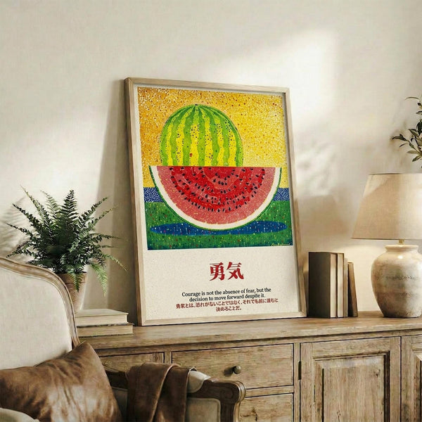 May include: Framed poster with colorful pointillism-style watermelon artwork against yellow dotted background, displayed on rustic wooden sideboard in cozy living room. Features Japanese characters and English text below the fruit illustration. Room setting includes white armchair, potted fern, ceramic vases, and books on weathered wood furniture.