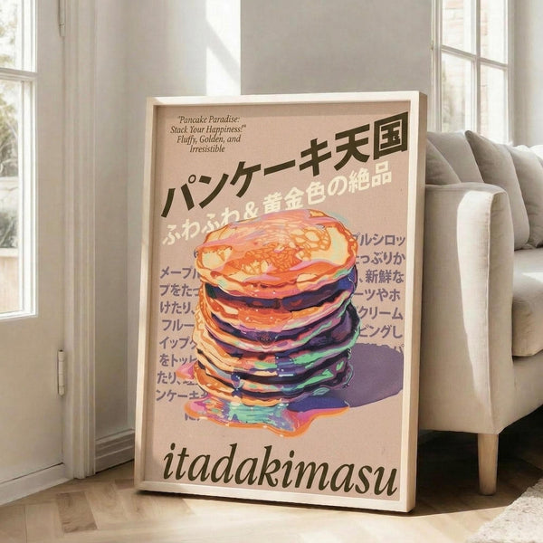 May include: Framed poster leaning against white wall next to beige sofa in bright room with large windows. Poster features stack of colorful pancakes with syrup dripping down, painted in vibrant oranges, purples, and blues against peachy background. Japanese text fills upper portion with "itadakimasu" in black letters at bottom. Light wooden frame surrounds artwork.