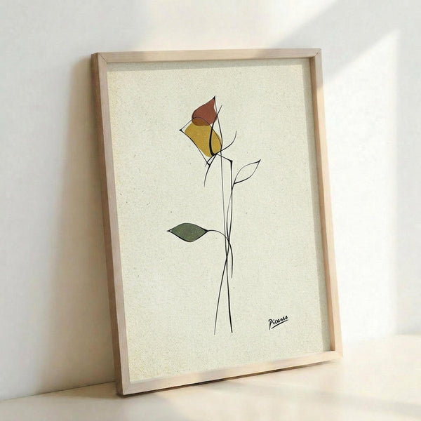 May include: Framed minimalist line drawing of a single rose with geometric colored petals in yellow and rust tones, displayed in a light wood frame against a cream textured background on a white wall. The artwork features simple black line work with selective color fills and includes an artist signature in the bottom right corner.