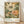 May include: Framed botanical art print leaning against white wall on light wood floor. Features large stylized flowers in cream, coral, and orange tones with detailed dotted patterns against dark green background. Japanese text and "Modern Art 1940 TOKYO" appear below artwork. Natural wood frame with white mat. Soft window light creates gentle shadows on textured white wall.