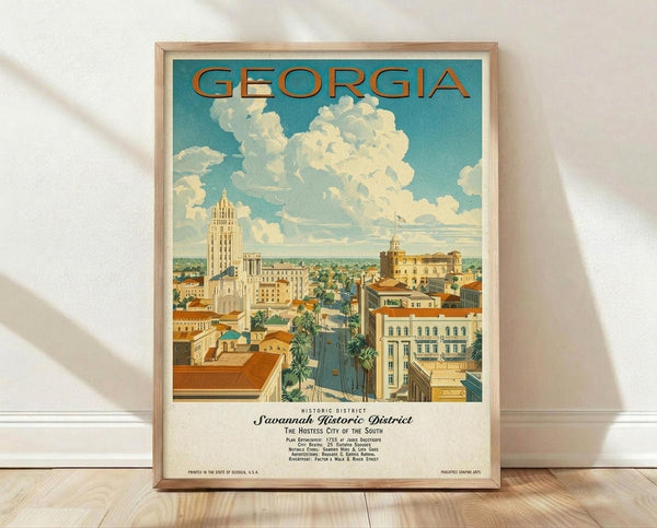 May include: Framed vintage-style travel poster featuring Savannah's historic district with tall Art Deco buildings, palm-lined streets, and puffy white clouds against turquoise sky. Poster shows "GEORGIA" in orange letters at top, displayed in light wood frame leaning against white wall on wooden floor with soft natural lighting.