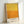 May include: Framed art print with yellow and orange color field design in thick, textured brushstrokes. The abstract painting transitions from bright yellow at top to warm orange at bottom. White text at bottom reads "MARK ROTHKO" and details about the color field series. Light wood frame sits against white wall, casting subtle shadow.