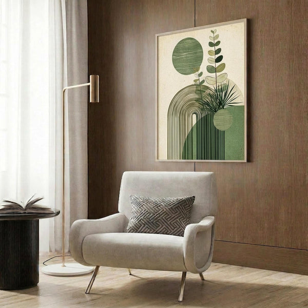 May include: Modern beige armchair with geometric pillow in contemporary room setting with wood paneled walls. Abstract botanical wall art features green circles, arches, and plant silhouettes in cream frame. Gold floor lamp and dark round side table with open book complete the neutral-toned interior scene.