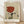 May include: Framed art print leaning against white wall on light wood floor. The poster features a minimalist illustration of hands holding a wine glass filled with red wine, with two large eyes peering from below. The artwork uses muted earth tones - beige, rust red, olive green, and black line work on textured paper background. French text "Plaisir des yeux" appears at bottom in red lettering. Natural wood frame surrounds the print.