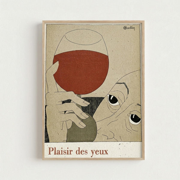 A minimalist art print in a light wood frame showing an abstract illustration of a person holding a wine glass filled with red wine. The artwork features muted earth tones with beige, rust red, and olive green colors against a textured cream background. Large stylized eyes are prominently featured in the composition. The text "Plaisir des yeux" appears at the bottom in brown lettering. The framed print is displayed against a white wall.