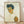 May include: Framed reproduction of an expressionist self-portrait showing a young man with tousled dark hair and angular features, rendered in earthy tones of yellow, orange, and blue against a cream background. The artwork is displayed in a light wood frame, leaning against a white wall on light wooden flooring with soft natural lighting creating subtle shadows.