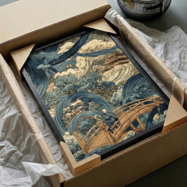 May include: Japanese woodblock print artwork in black frame being unpacked from cardboard shipping box with protective tissue paper. The print depicts a dramatic storm scene with swirling blue and cream colored waves surrounding a wooden bridge structure, with a small figure visible on the bridge. The vintage-style artwork shows traditional ukiyo-e aesthetic with flowing water patterns and detailed linework in blues, browns, and beige tones.