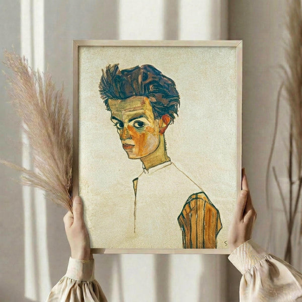 May include: Person in cream dress holding framed reproduction of expressionist self-portrait featuring young man with tousled dark hair, pale complexion, and white collar against beige background. Dried wheat stems visible beside frame in soft natural lighting near window with flowing curtains.