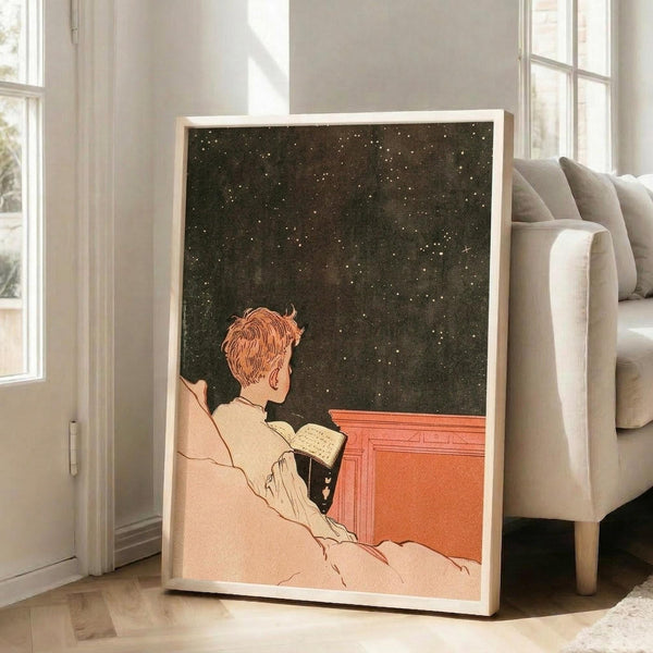 May include: Vintage-style poster print in light wood frame leaning against beige sofa in bright living room with large windows. Artwork shows person with reddish hair in cream clothing reading book while gazing at starry night sky, rendered in muted earth tones with dark green starfield background and coral-orange architectural elements.