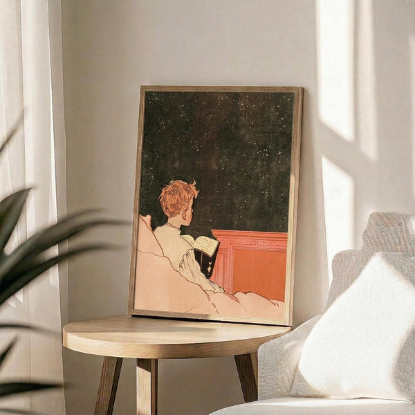 May include: Framed vintage-style poster showing person in cream clothing reading a book while looking at starry night sky, displayed on round wooden side table next to beige armchair with white pillow and plant leaves visible, soft natural lighting creating shadows on white walls