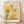 May include: Framed botanical art print leaning against white wall on light wood floor. The poster features abstract yellow and green foliage with dotted patterns and small flowers in warm earth tones. Text reads "YAYOI KUSAMA" at top and "Modern Art 1996" at bottom. Natural wood frame surrounds cream-colored background with organic plant motifs in contemporary artistic style.