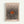 Framed art print featuring a radiating pattern of black polka dots emanating from a central orange oval on a beige background. The dots start small at the center and gradually increase in size toward the edges, creating an optical illusion effect. Text reads "YAYOI KUSAMA" at the top, "Modern Art" and "1975" at the bottom. Displayed in a light wood frame against a white wall.