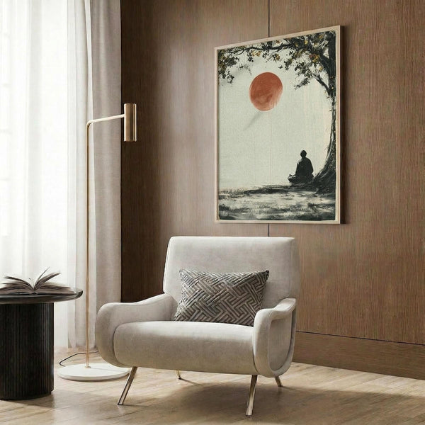 May include: A framed zen artwork showing a silhouetted monk meditating under a tree branch with a large red sun above, displayed on warm wood paneling behind a cream upholstered armchair with geometric throw pillow, brass floor lamp, and dark round side table with open book in a modern living room setting.