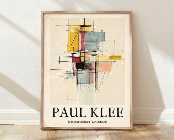 May include: Framed abstract art print in light wood frame leaning against white textured wall on wooden floor. Artwork features geometric composition with yellow, blue, red, and pink rectangular shapes intersected by black linear grid lines on cream background. Modern minimalist room setting with soft natural lighting casting shadows.
