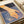 A hand extends down toward rippling water in warm golden and orange tones against a deep blue background. The word "Still" appears in white text at the top. The artwork shows textured brushstrokes and flowing water patterns. The print is displayed on white paper with a beige ribbon visible at the edge.