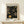 May include: Framed poster print with black background and golden circular dot patterns in concentric rings, displayed on light wood shelf against white wall. Small white wrapped gift box with greenery sits beside the wooden frame. Abstract geometric design features various sized circles and dotted spiral motifs in gold and yellow tones.