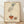 May include: Framed vintage French fashion illustration showing an elegant hand with ruffled sleeve dropping jewelry into an ornate bowl. Art features muted earth tones on cream textured paper with French text below. Natural wood frame sits on light wooden floor against white wall with soft natural lighting creating gentle shadows.