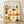 May include: Framed poster with twelve illustrated portrait squares showing diverse people in colorful clothing and accessories. Hand-drawn style artwork features characters in sweaters, hats, and glasses with warm tones of orange, yellow, green, and pink. Black text "SOIS UNIQUE" appears at top. Light wood frame sits against white wall on wooden floor with soft natural lighting creating gentle shadows.