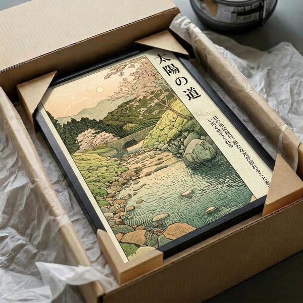 May include: Japanese woodblock print in black frame showing serene landscape with cherry blossoms, green hills, rocky stream, and pale moon in peachy sky. Print sits in open cardboard shipping box with tissue paper and wooden dowels for protection. Traditional ukiyo-e art style with soft earth tones and detailed nature scene.