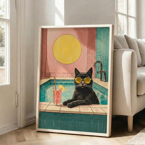 May include: Framed art print displayed in bright living room showing a black cat wearing yellow sunglasses lounging by a turquoise swimming pool. The vintage-style illustration features coral pink and teal walls, a large yellow sun, and a tropical drink with straw nearby. White frame leans against wall next to beige sofa.