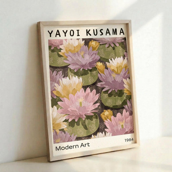 May include: Framed poster print featuring colorful water lilies in pink, purple, yellow and white with green lily pads on dark background, displayed in light wood frame leaning against white wall. Text reads "YAYOI KUSAMA" at top, "Modern Art" and "1984" at bottom. Artwork shows painterly floral pattern in soft, muted tones with dotted textures throughout.