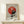 May include: Framed Bauhaus-inspired geometric poster with red and black circle design, vertical lines, and "Ausstellung 1919" text, displayed on light wood table with small wrapped gift beside it against cream wall