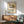 May include: Framed vintage-style poster featuring a modernist cantilever chair with cane backrest, blue seat cushion, and yellow geometric circle accent against cream background. Displayed above wooden credenza with white ceramic lamp in mid-century modern living room setting with gray upholstered armchair and natural lighting casting geometric shadows on white wall.