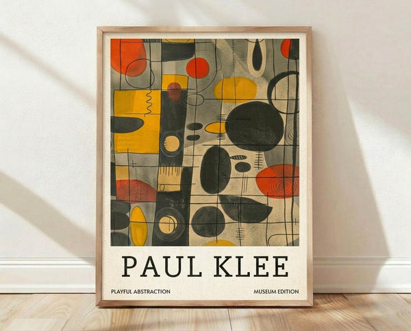 May include: Framed abstract art poster featuring geometric shapes in orange, yellow, and dark green on beige background, displayed in light wood frame against white wall on wooden floor with natural shadows