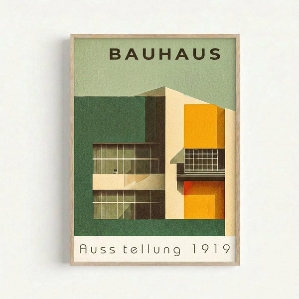 Framed vintage-style poster with green background featuring modernist architectural building illustration. The structure shows geometric forms in yellow, orange, and cream with grid windows and clean lines. Text reads "BAUHAUS" at top and "Ausstellung 1919" at bottom in sans-serif font. Natural wood frame against white wall with subtle shadow.