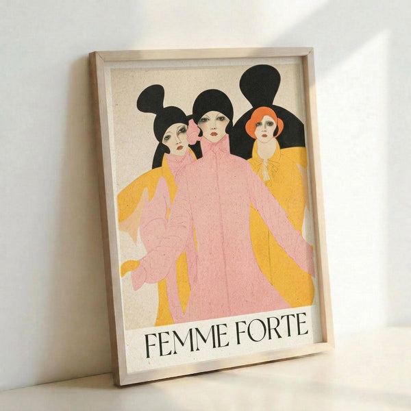 May include: Framed vintage-style poster featuring three women with black hair in pink and yellow flowing garments against cream background, with "FEMME FORTE" text below. Art deco-inspired illustration in light wooden frame, leaning against white wall with soft natural lighting creating gentle shadows.