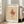 May include: Framed Paul Klee modernist artwork print leaning against white wall next to beige sofa. Abstract composition features geometric shapes in pink, orange, and black tones on cream background with linear elements. Light wooden frame, museum edition text visible. Bright natural lighting from windows creates soft shadows on wooden floor.
