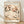 May include: A framed art print leaning against a white wall on light wood flooring. The poster features delicate cherry blossom branches with pink and white flowers against a cream background, displayed in a thin natural wood frame. Soft natural lighting creates gentle shadows on the textured white wall behind the artwork.