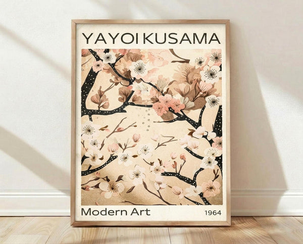 May include: A framed art print leaning against a white wall on light wood flooring. The poster features delicate cherry blossom branches with pink and white flowers against a cream background, displayed in a thin natural wood frame. Soft natural lighting creates gentle shadows on the textured white wall behind the artwork.