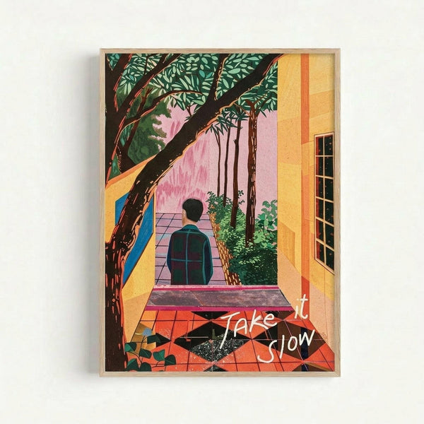 May include: Framed colorful illustration poster on white wall showing person in dark clothing sitting on terrace with orange tile floor, surrounded by lush green foliage and trees. Scene features yellow building walls, pink sky, and handwritten white text reading "Take it Slow" in corner. Natural wood frame, bright tropical colors with peaceful, contemplative mood.