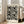 May include: Framed art print with black polka dots of varying sizes on white background, displayed in light wood frame leaning against white wall next to beige upholstered chair in bright, airy room with large windows and natural light streaming across hardwood floors.