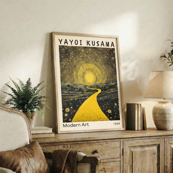 May include: Framed art print featuring a dotted landscape with yellow winding path leading to bright sun against dark starry sky, displayed on rustic wooden sideboard alongside fern plant, ceramic vase, and books in neutral-toned living room setting.