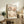 May include: Framed poster print displayed on rustic wood sideboard in neutral-toned living room. Artwork features delicate cherry blossom branches with pink flowers and dark spotted branches on cream background, with "YAYOI KUSAMA" and "Modern Art 1964" text. Scene includes fern plant, ceramic vases, books, and beige upholstered furniture in soft natural lighting.
