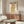 May include: Vintage Japanese owl poster with geometric patterns in warm brown and orange tones, featuring Japanese text and "International Peace Society" branding. The framed artwork is displayed above a mid-century modern walnut credenza with sliding doors. A curved white chair and oval glass coffee table with colorful abstract design complete the minimalist living room scene with white walls and natural lighting.