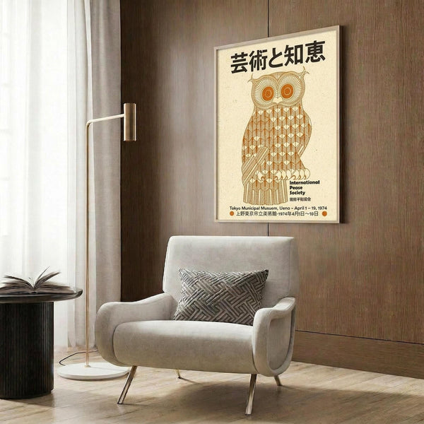 May include: Vintage-style poster featuring stylized orange owl with geometric patterns and Japanese text, displayed in light wooden frame on wood panel wall above beige upholstered armchair with geometric throw pillow, brass floor lamp and round black side table with open book nearby