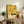 May include: Abstract art poster with yellow and cream background featuring black geometric shapes, orange accents, and flowing lines in mid-century modern style. Framed print displayed on rustic wooden sideboard alongside fern plant, ceramic vases, and books in neutral-toned living room setting.