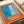 A vintage-style poster with an orange border featuring an abstract pool or water scene. The artwork shows blue water with wavy lines on the left, light blue splashing water in the center, and blue tiled areas. French text "Plonge dans le grand bain" appears in white letters at the bottom. The poster is displayed on white paper with a beige ribbon visible in the corner.