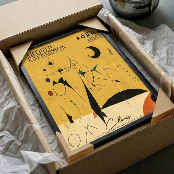 May include: Abstract art print with yellow background featuring geometric shapes, curved lines, and colorful forms in Miro's distinctive style. Black frame shown in cardboard shipping box with protective wrapping materials on white surface.