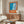 May include: Orange-framed art print with blue swimming pool illustration and French text displayed on wooden credenza in modern living room with white curved chair, glass coffee table, and floor lamp