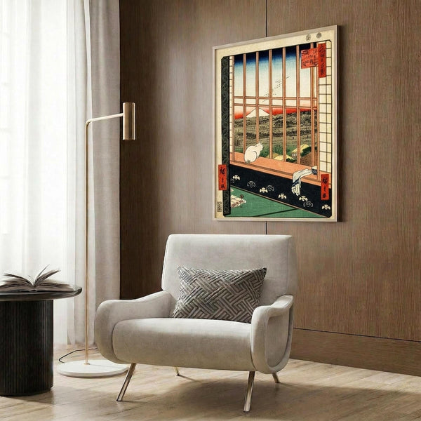 May include: Japanese woodblock print artwork displayed in modern reading nook with cream armchair, geometric pillow, brass floor lamp, and dark round side table with open book. The framed print shows traditional interior scene with wooden lattice window, tatami mats, and mountain landscape view in vintage ukiyo-e style with red, blue, and green colors against warm wood paneled wall.