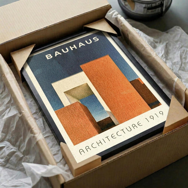 May include: Framed Bauhaus-style architectural poster with geometric orange, blue, and cream colored shapes on dark background, displayed in wooden box with tissue paper and wooden dowels, creating vintage mid-century modern aesthetic