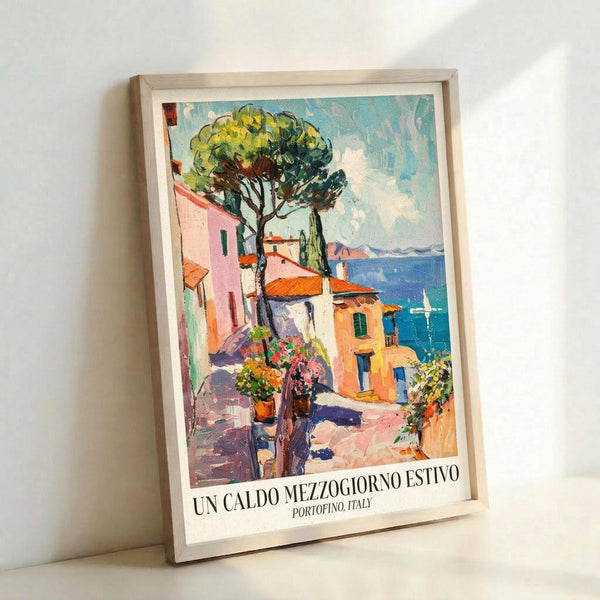 May include: Framed vintage-style travel poster featuring a colorful Mediterranean coastal scene with pastel buildings, terracotta roofs, large green tree, and blue ocean view. The artwork shows an impressionistic painting style with vibrant colors including pink, orange, yellow and turquoise. Italian text appears at bottom. Light wood frame against white wall in minimalist setting.