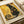Black cat artwork in Gustav Klimt's distinctive Art Nouveau style, featuring golden geometric patterns and spirals surrounding an elegant seated cat with bright eyes. The decorative poster has ornate circular motifs, checkered designs, and rich gold and black coloring reminiscent of Klimt's famous paintings. Text reads "NINE LIVES OF LUXURY" and "NO PAWS IN MY PLANS, ONLY PURRRFECTION" below the artistic cat illustration.