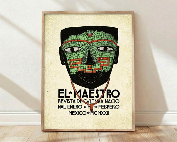 May include: Framed vintage-style poster featuring an ornate mosaic mask in green and red tiles with white eyes, displayed in a light wood frame against a cream textured background. The mask has decorative geometric patterns and the poster includes black Spanish text below. The frame leans against a white baseboard on light wooden flooring with natural shadows cast across the scene.