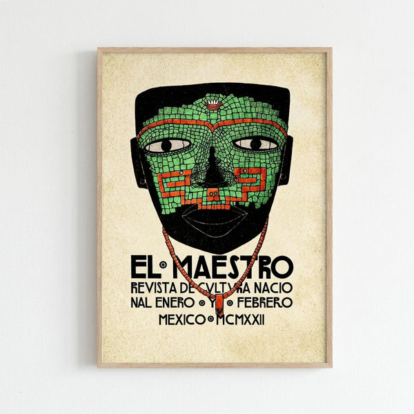 A framed vintage-style poster featuring an Aztec ceremonial mask with intricate green mosaic tilework and red geometric patterns. The mask has white eyes with black pupils and displays traditional stepped designs. Below the mask, black text reads "EL MAESTRO REVISTA DE CULTURA NACIONAL ENERO Y FEBRERO MEXICO MCMXXII" on a cream-colored background. The artwork is displayed in a light wood frame against a white wall.